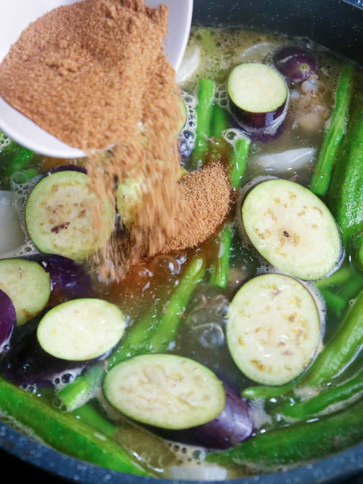 adding tamarind powder to a pot of sinigang