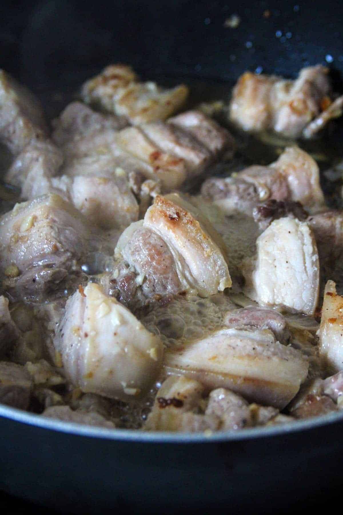cooking adobong baboy in a pan