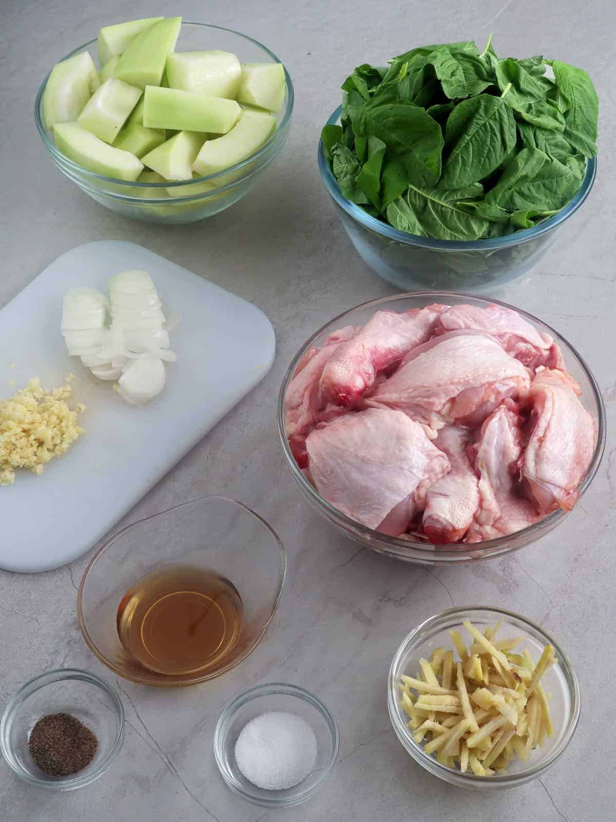 cut up chicken, spinach, cubed green papaya, julienned ginger, fish sauce, chopped onions, minced garlic in individual bowls