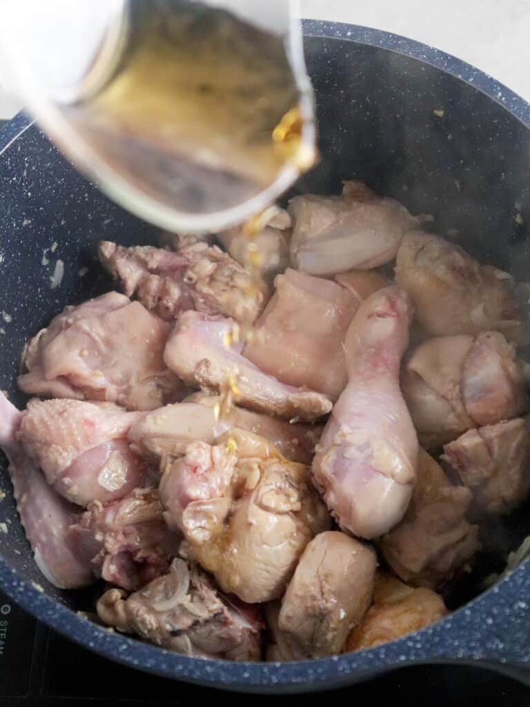 adding fish sauce to sauteed chicken in a pot