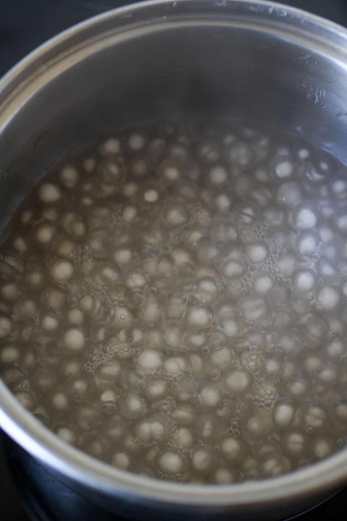 cooking sago in a pot of boiling water