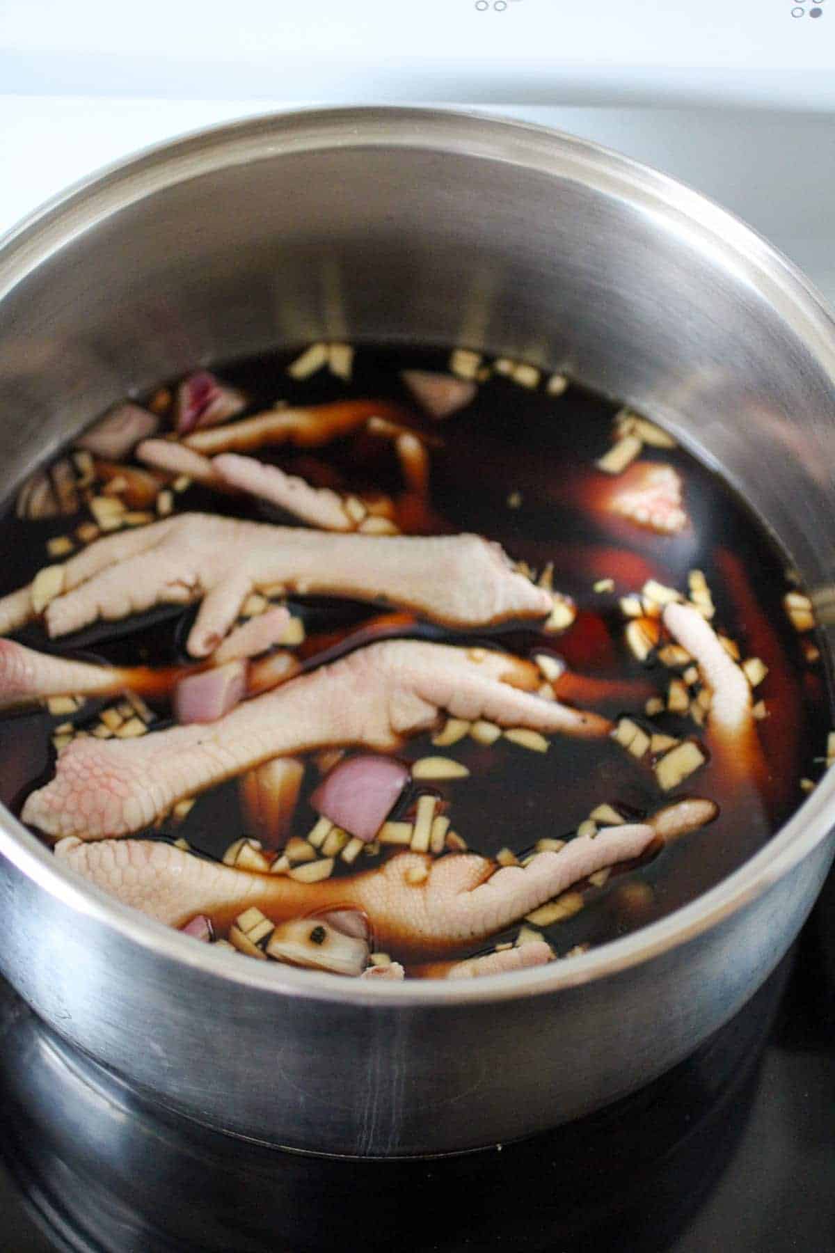 chicken paws in a pot of soy sauce, vinegar, minced garlic, and chopped onions