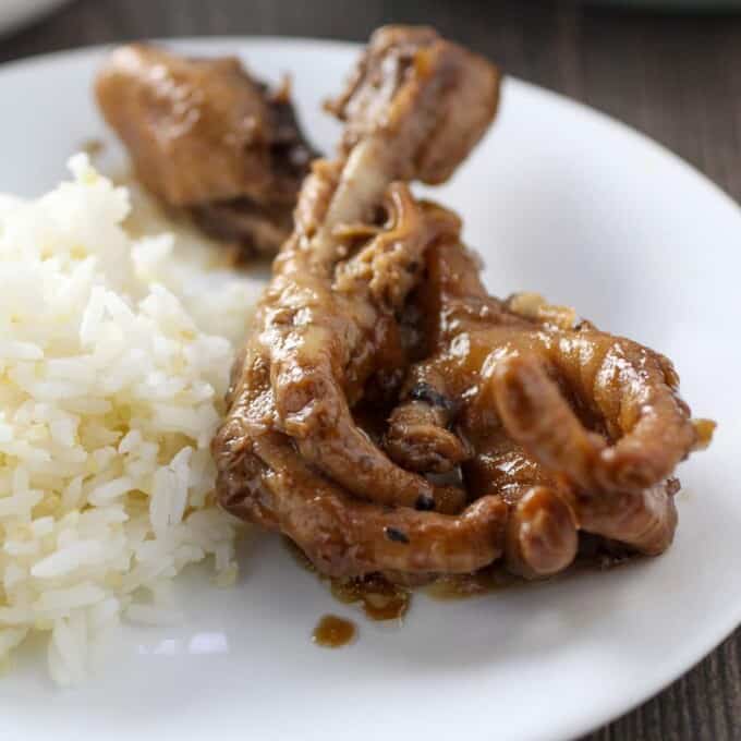 chicken feet adobo on white plate with steamed rice