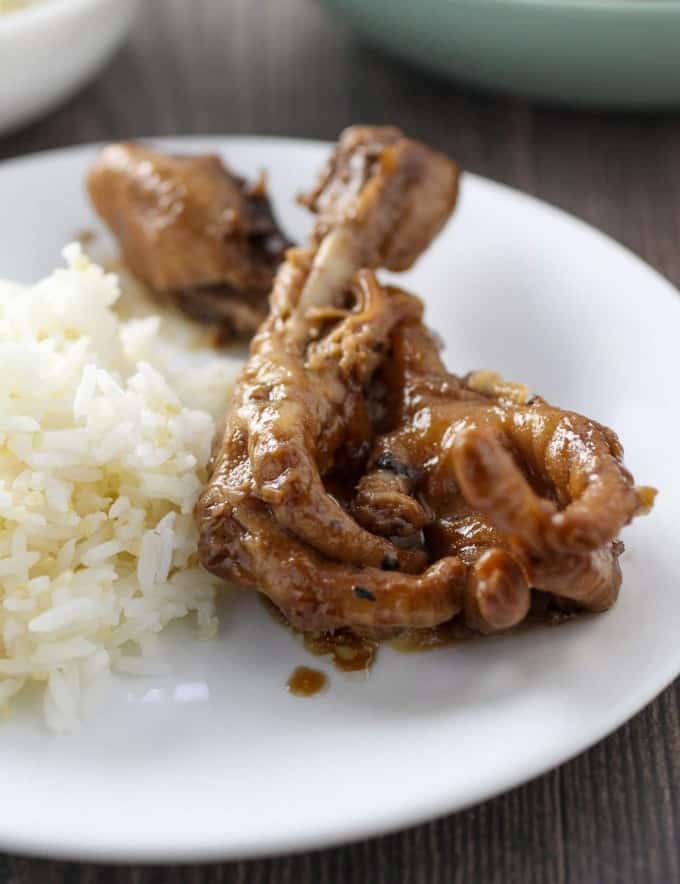 chicken feet adobo on white plate with steamed rice