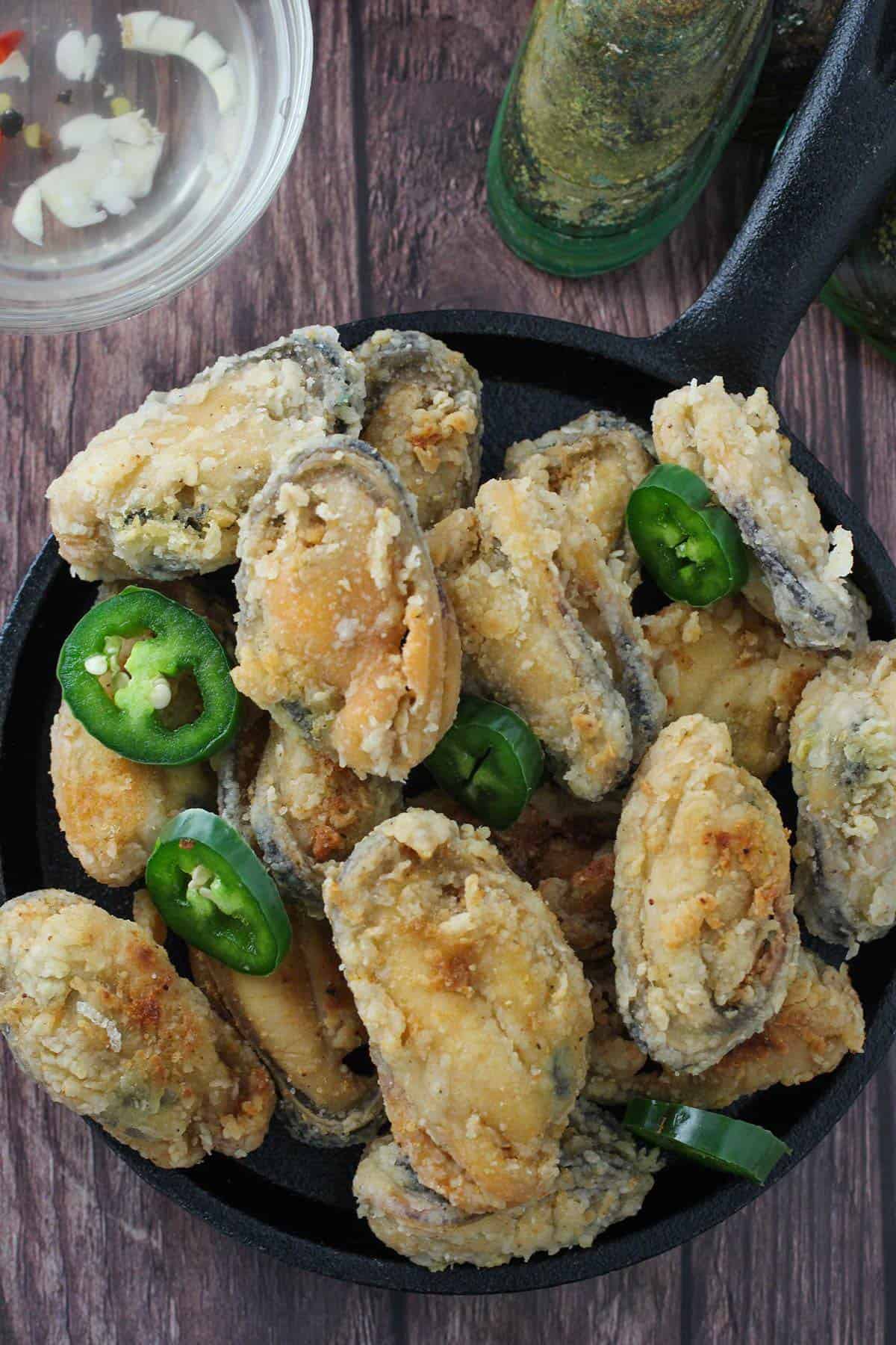 crispy tahong with sliced jalapenos on a cast-iron skillet
