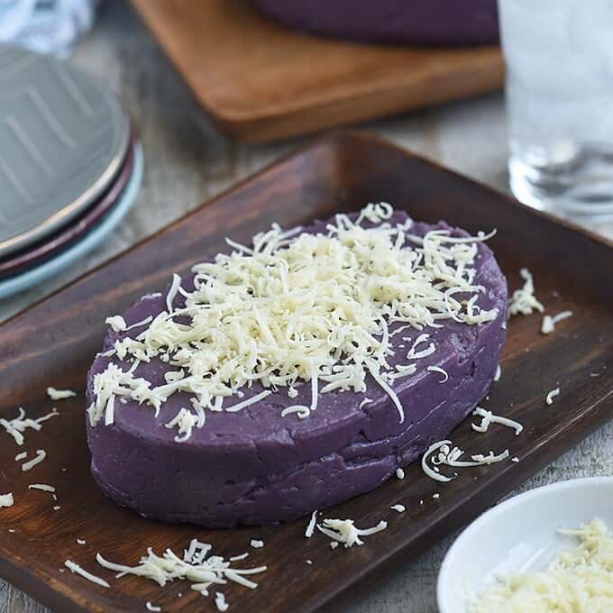 Halayang Ube topped with shredded cheese on a wooden platter