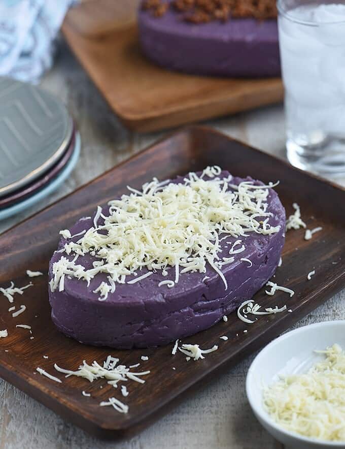 Halayang Ube topped with shredded cheese on a wooden platter