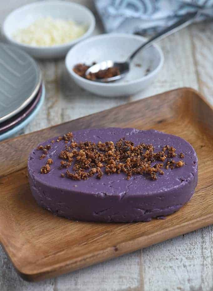 ube halaya topped with latik on a wooden serving platter