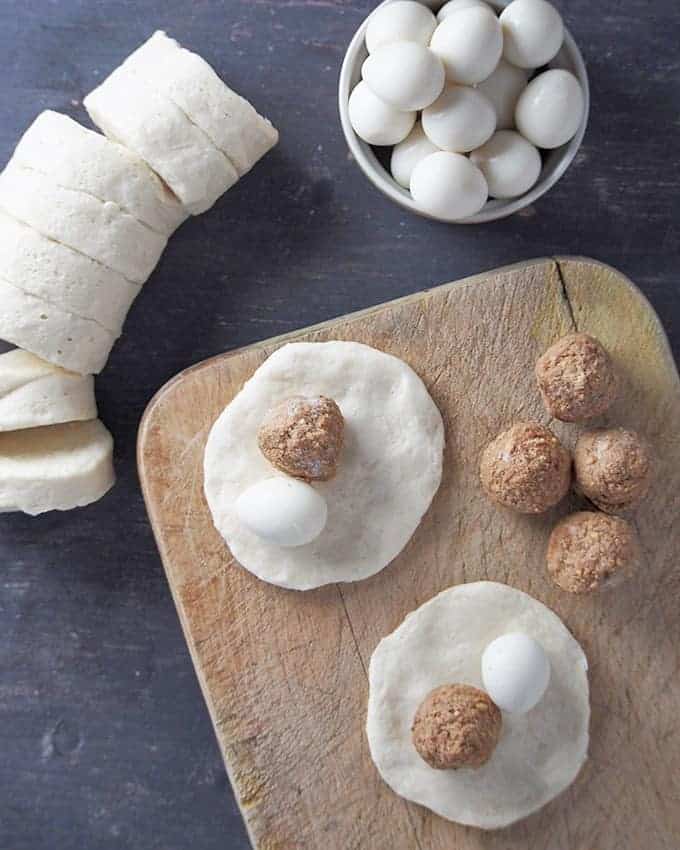 Place quail egg and frozen meatball in biscuit dough as preparation. 