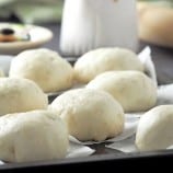 siopao bola bola on a baking sheet with white jug of siopao sauce on the side