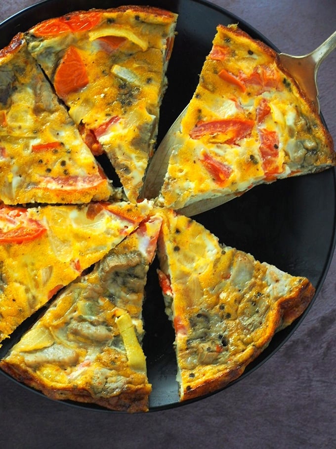sliced roasted eggplant and tomato frittata on a black serving plate