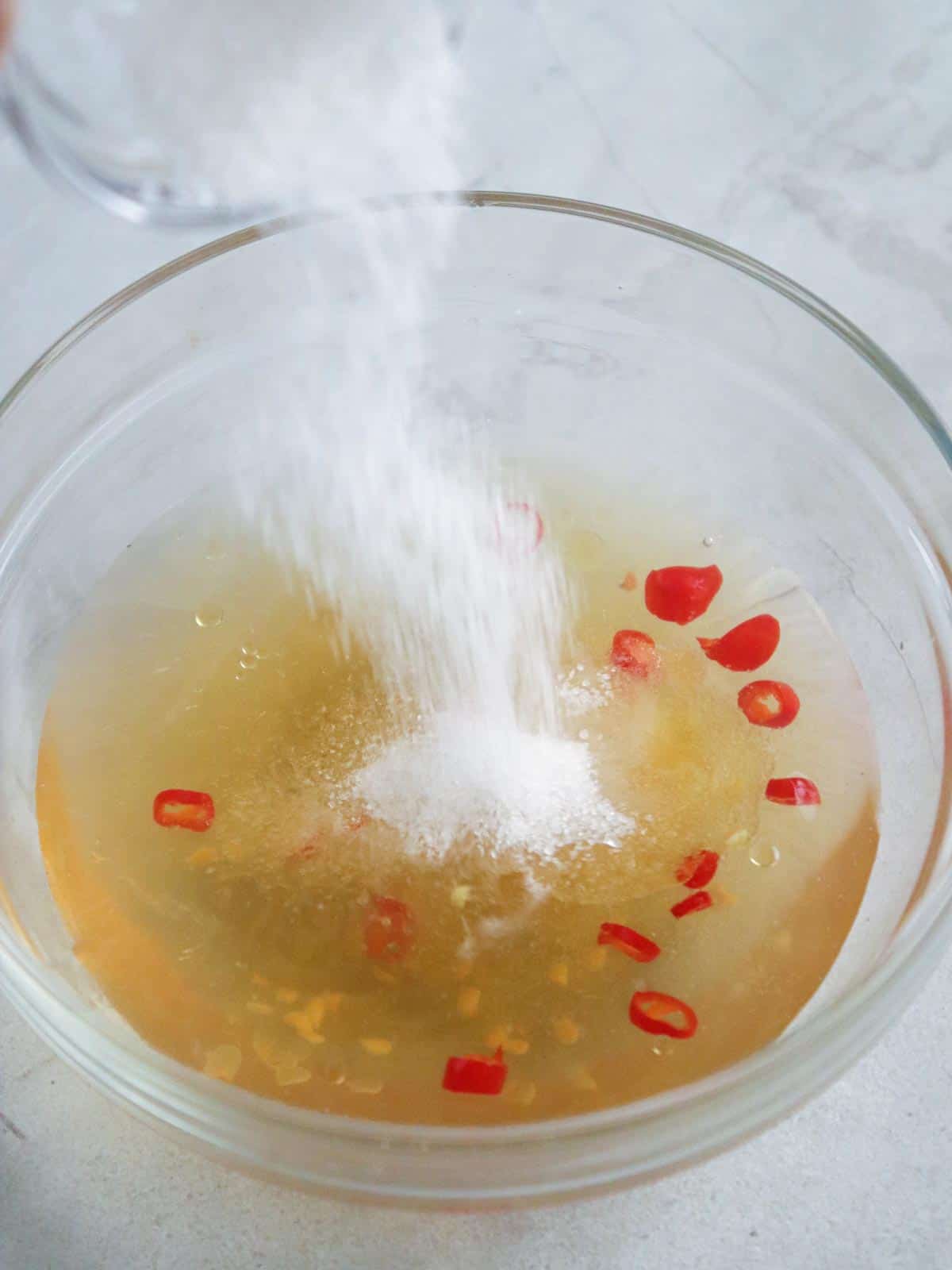 adding sugar to Filipino-style vinaigrette dressing in a bowl