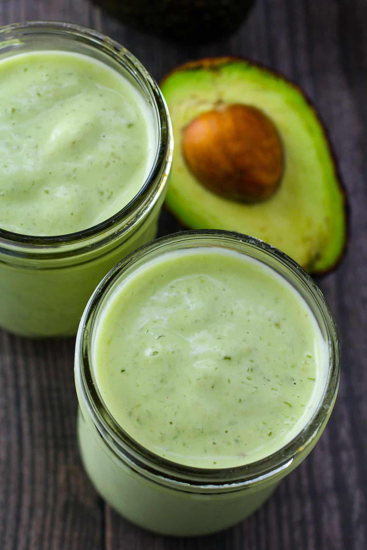 Avocado Milkshake in a glass with avocado half on the side