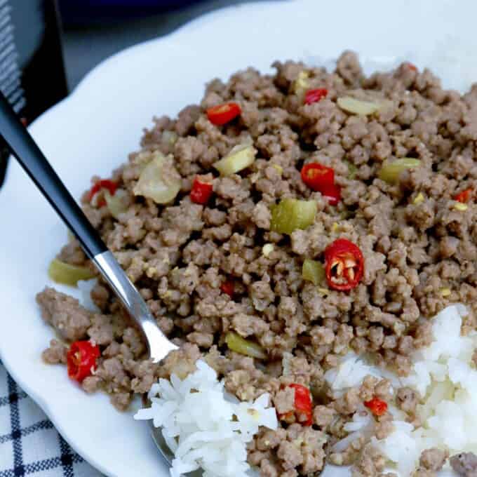 bagis with chopped red chili peppers over rice on a white serving plate