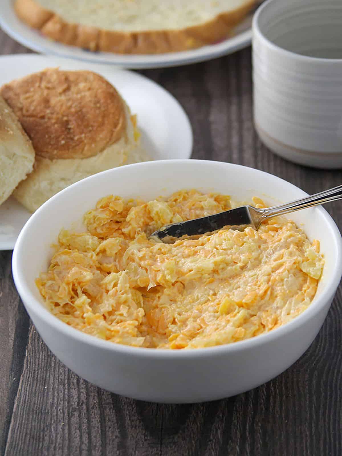 cheese pineapple spread in a white bowl with pandesal on the side