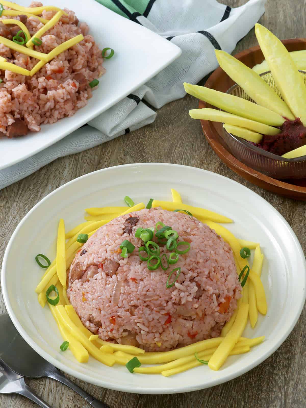 Binagoongan fried rice with sliced mangoes on a serving plate