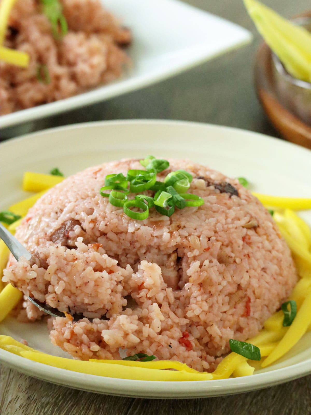 eating binagoongan rice with a fork on serving plate