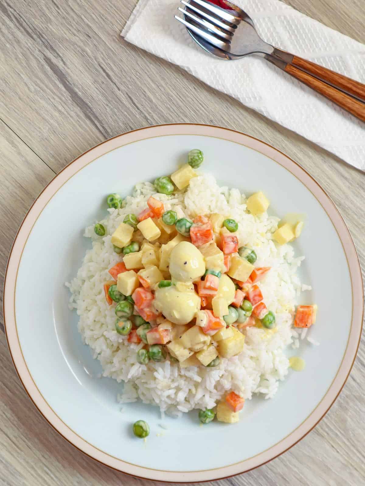 sipo eggs with carrots, green peas, singkamas, and quail eggs over rice on a white plate