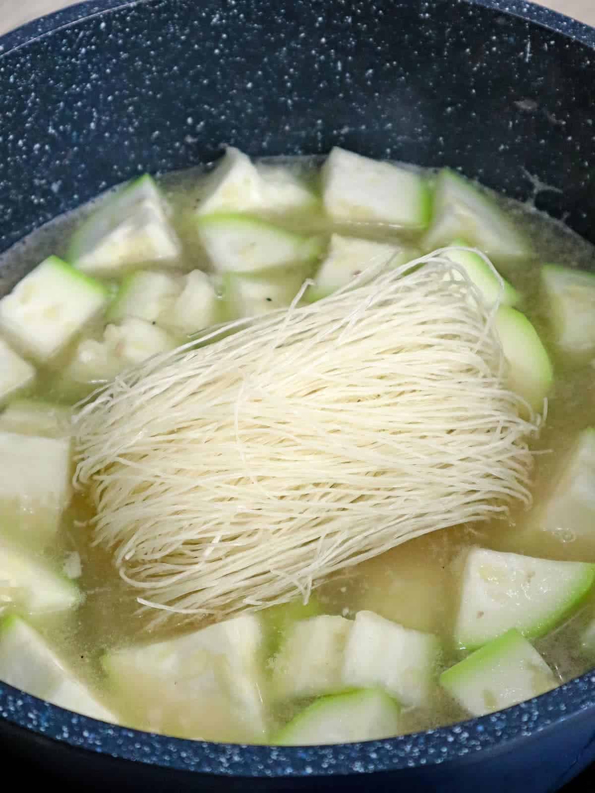 cooking sotanghon and upo with chicken in a pot