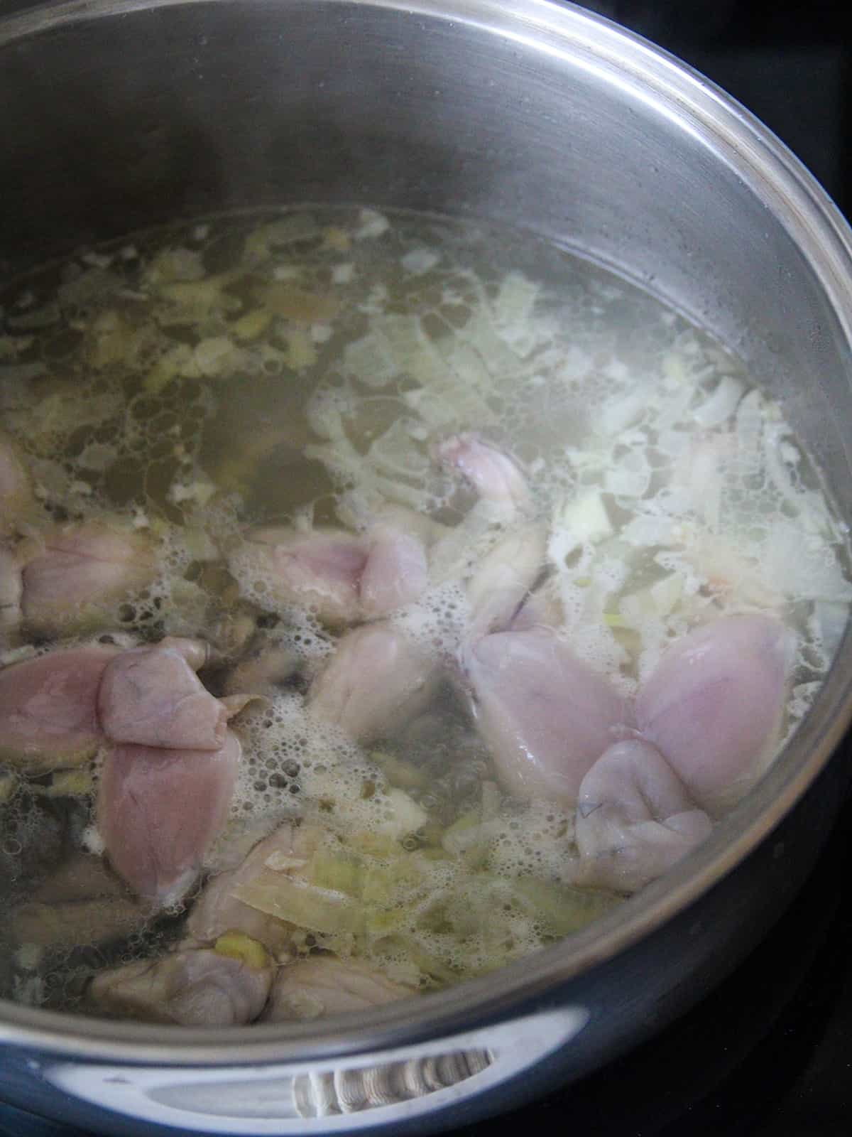 sauteing frog legs in garlic and onions in a pan.