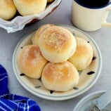 Pandesal on a plate with a cup of coffee on the side