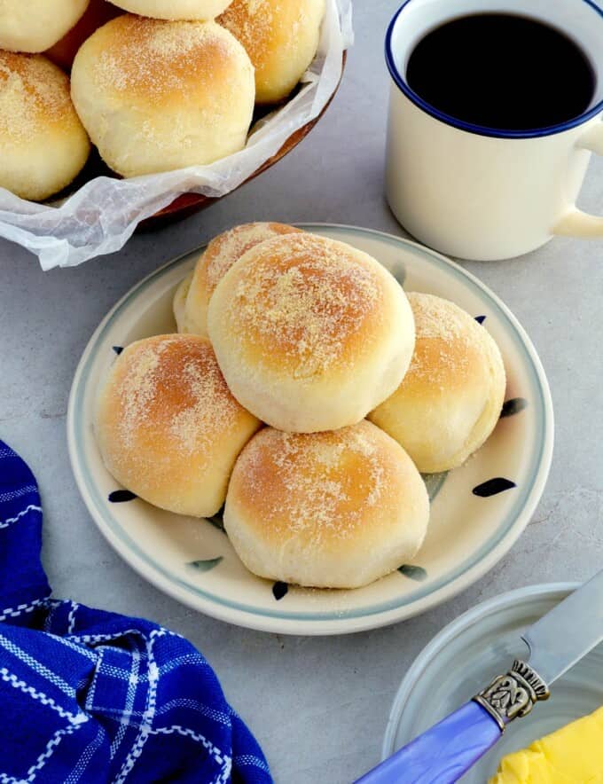 Pandesal on a plate with a cup of coffee on the side
