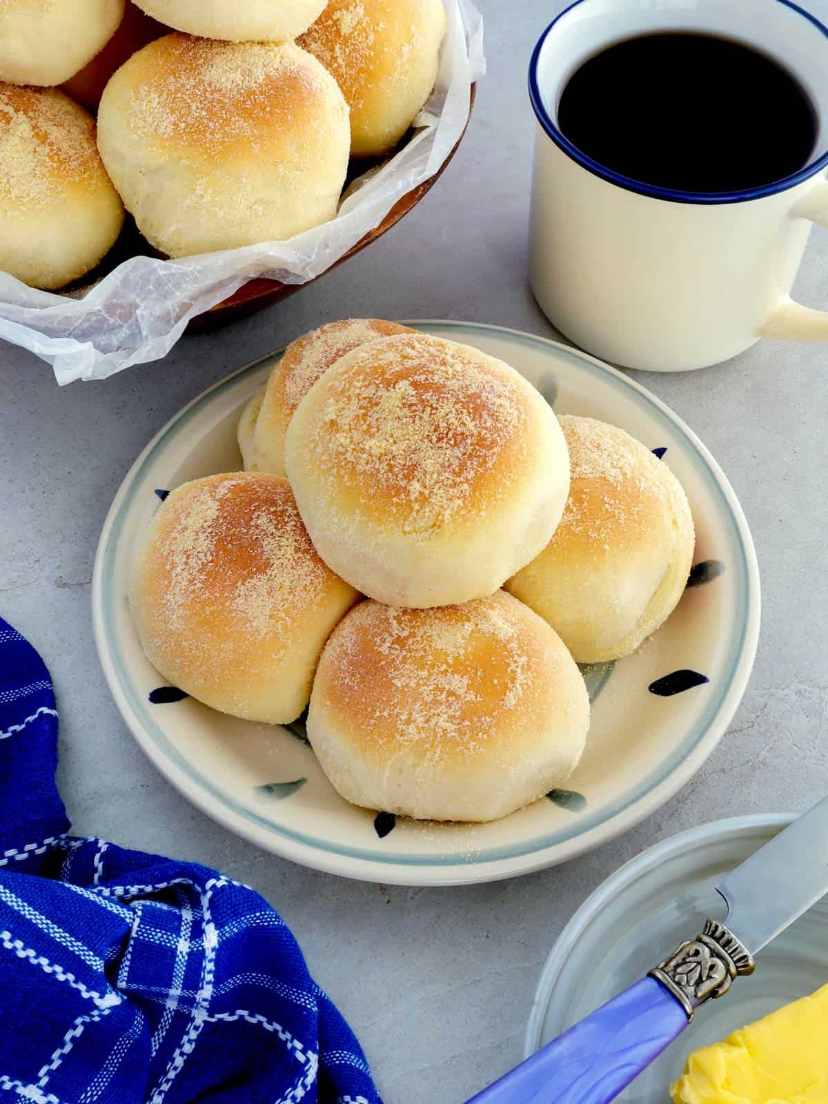 Pandesal on a plate with a cup of coffee on the side