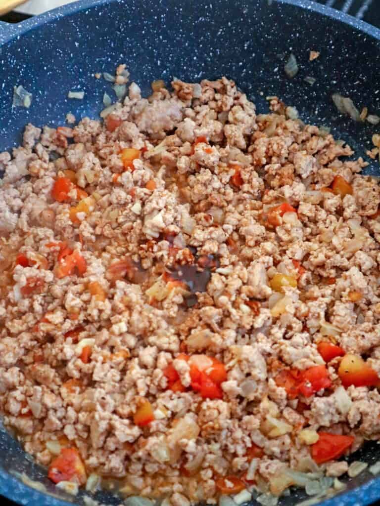 sauteing ground pork with tomatoes and oyster sauce in a pan