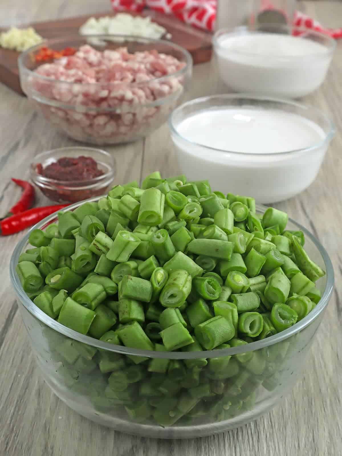 chopped green beans, ground pork, and coconut milk in individual bowls