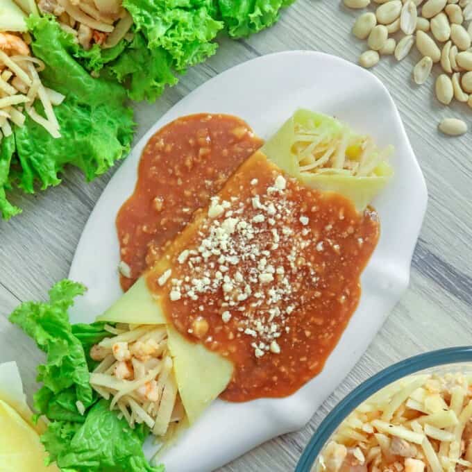 Lumpiang Ubod on a white plate with peanut sauce