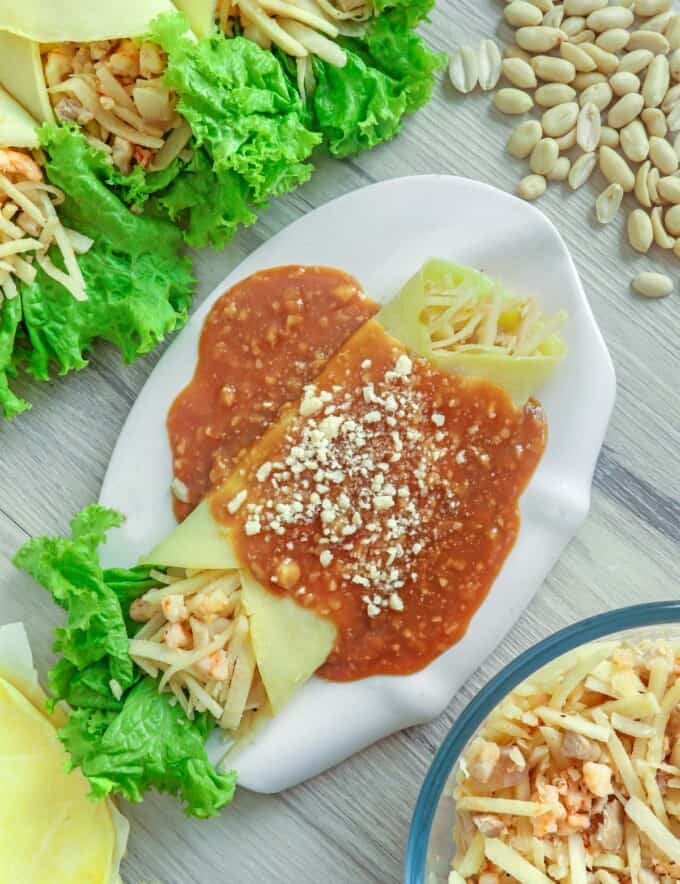 Lumpiang Ubod on a white plate with peanut sauce