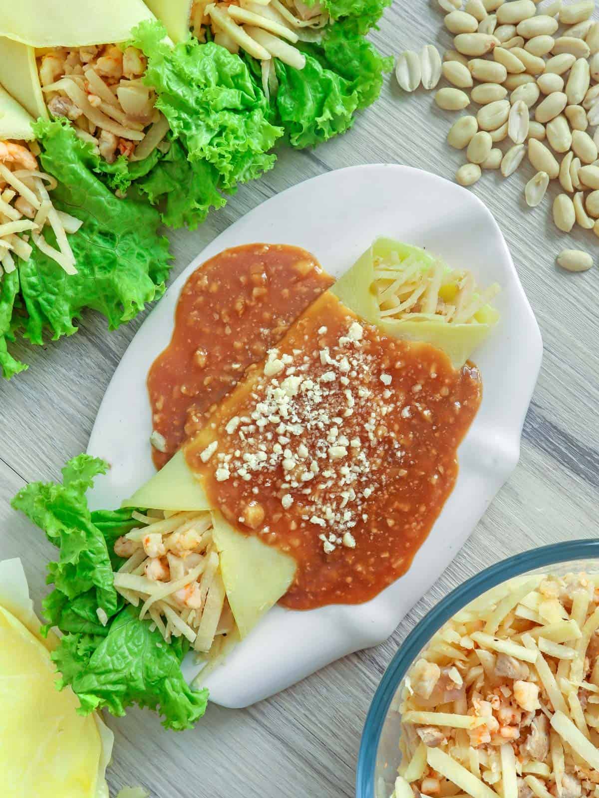 Lumpiang Ubod on a white plate with peanut sauce