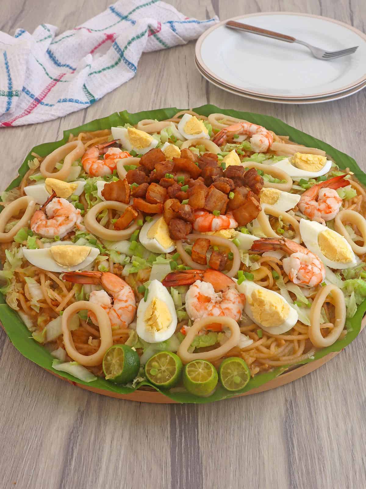 Pancit Malabon with assorted toppings on a bilao