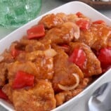 Sweet and Sour Fish in a white serving dish with a plate of steamed rice on the side