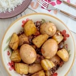 Adobong Itlog in a white serving bowl with a plate of steamed rice on the side