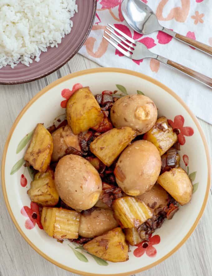 Adobong Itlog in a white serving bowl with a plate of steamed rice on the side