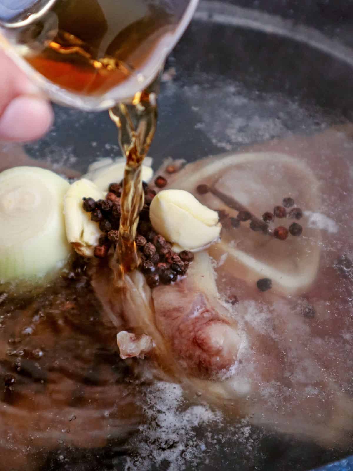 pouring fish sauce in a pot of boiling beef shanks