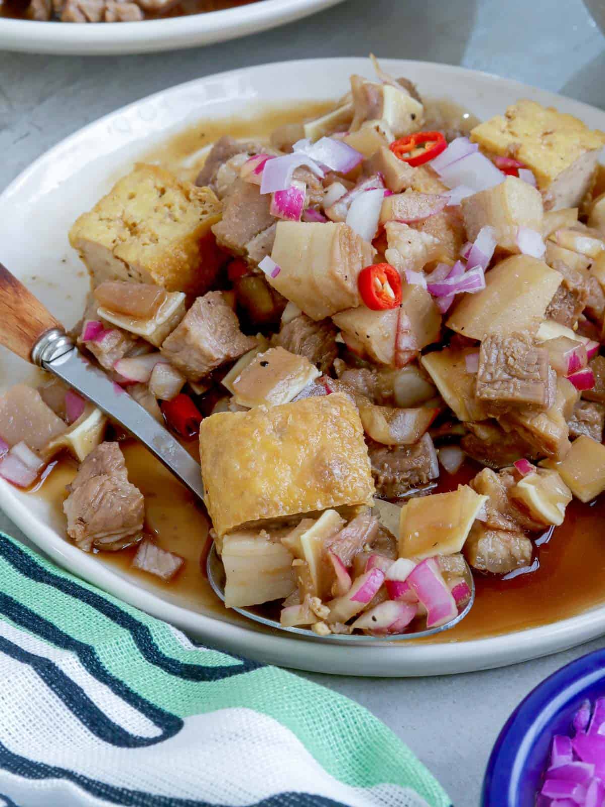 Tokwa't Baboy in a serving bowl with a wooden spoon