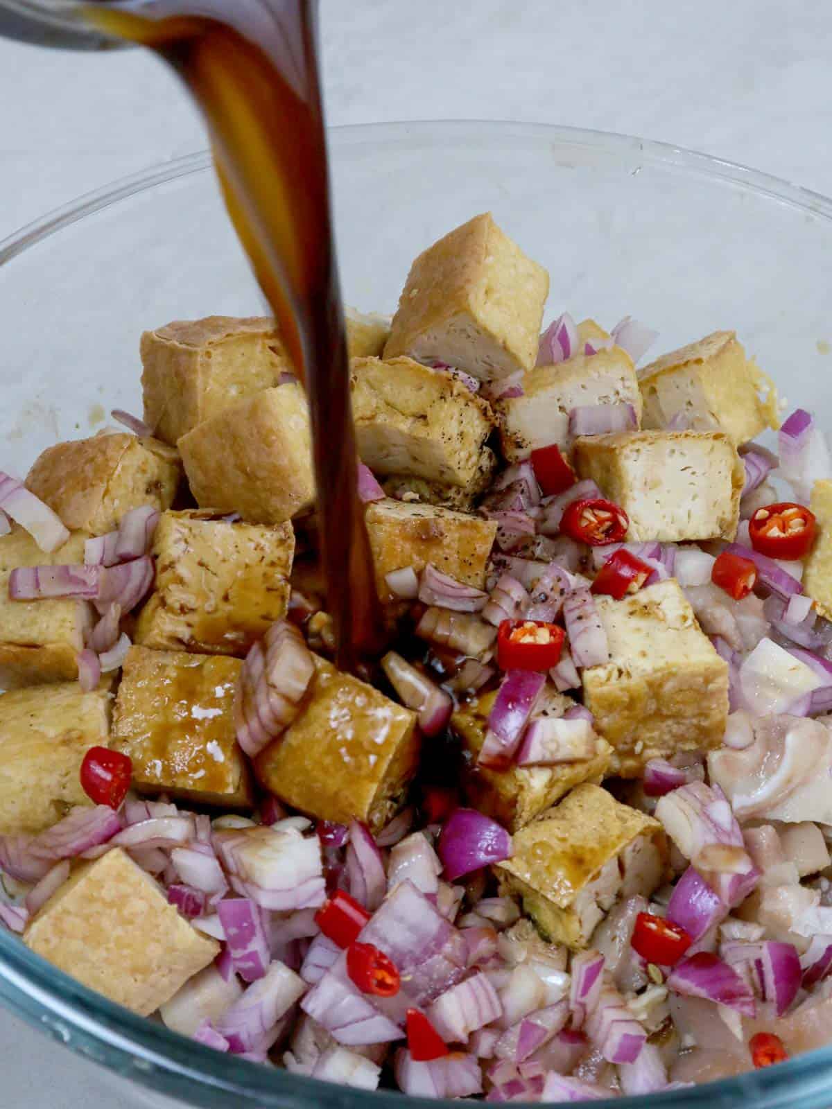 pouring vinegar-soy sauce mixture to a bowl of tokwa and baboy