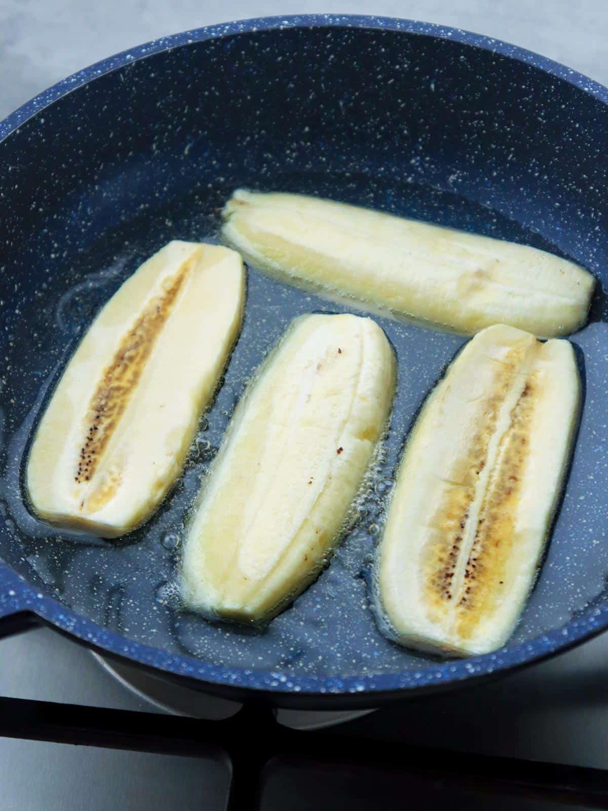 frying sliced saba bananas in a pan