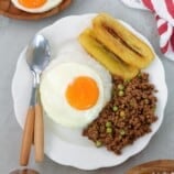 cuban rice with ground beef hash, fried egg, fried bananas, and white rice on white serving plate