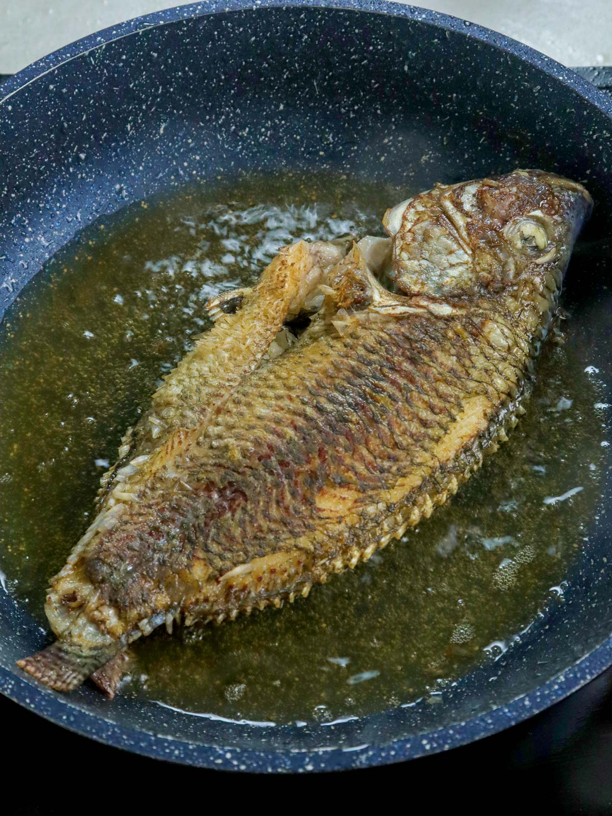 frying tilapia in a pan.