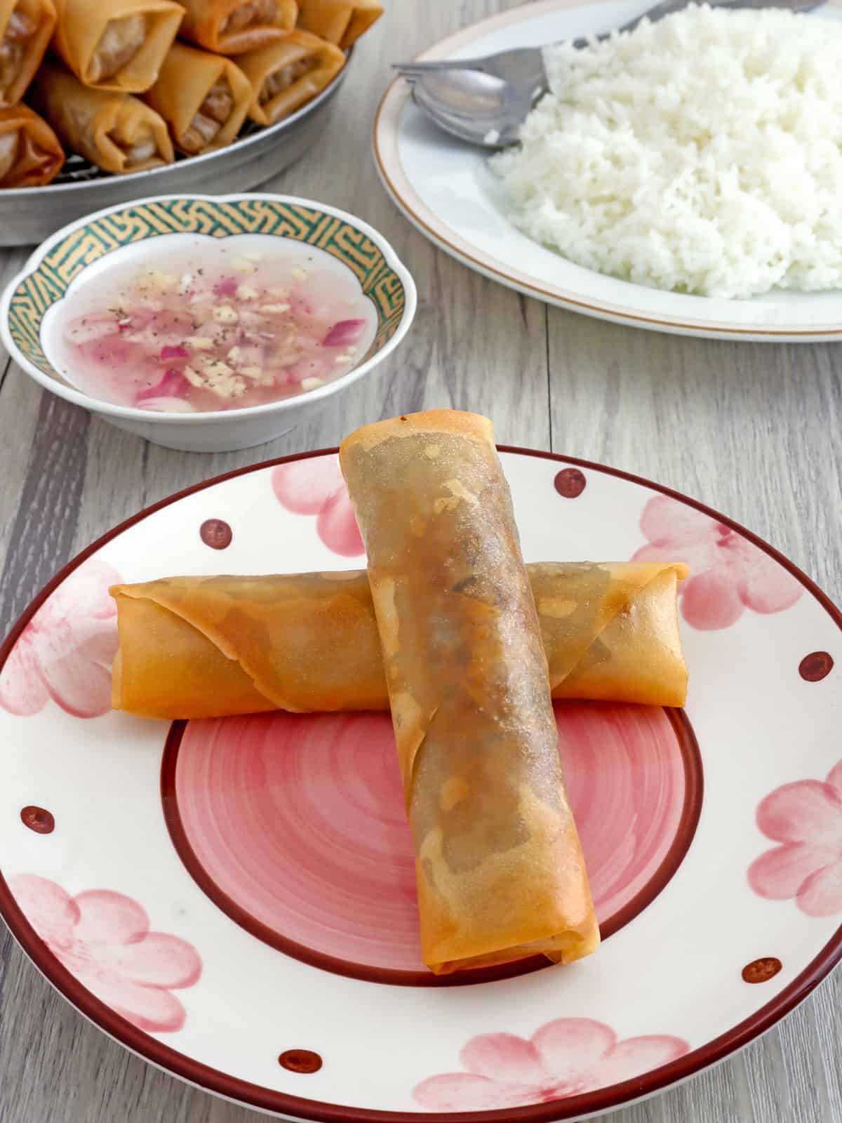 Lumpiang Puso ng Saging on a plate with spicy vinegar and steamed rice on the side