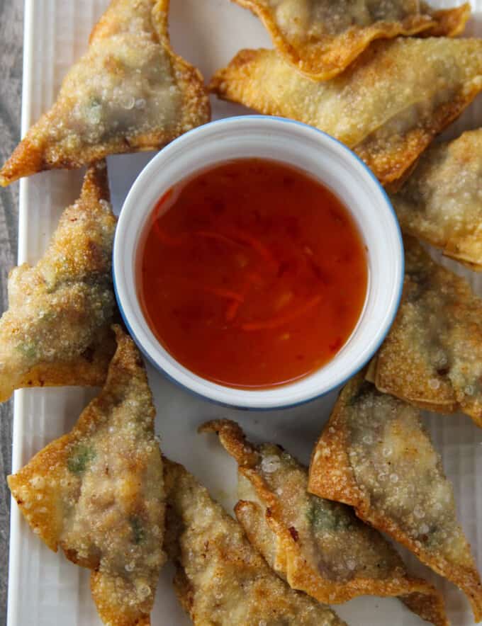 fried wontons on a serving platter with a bowl of sweet and sour dipping sauce