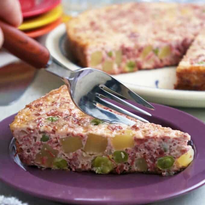 slice of frittata with corned beef, potatoes, and eggs on serving plate