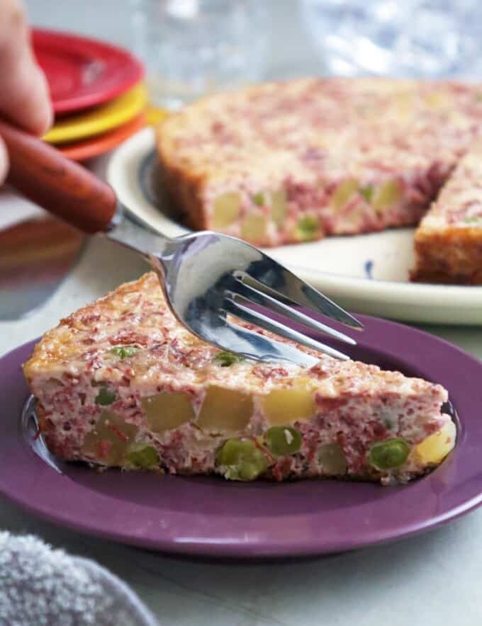 slice of frittata with corned beef, potatoes, and eggs on serving plate