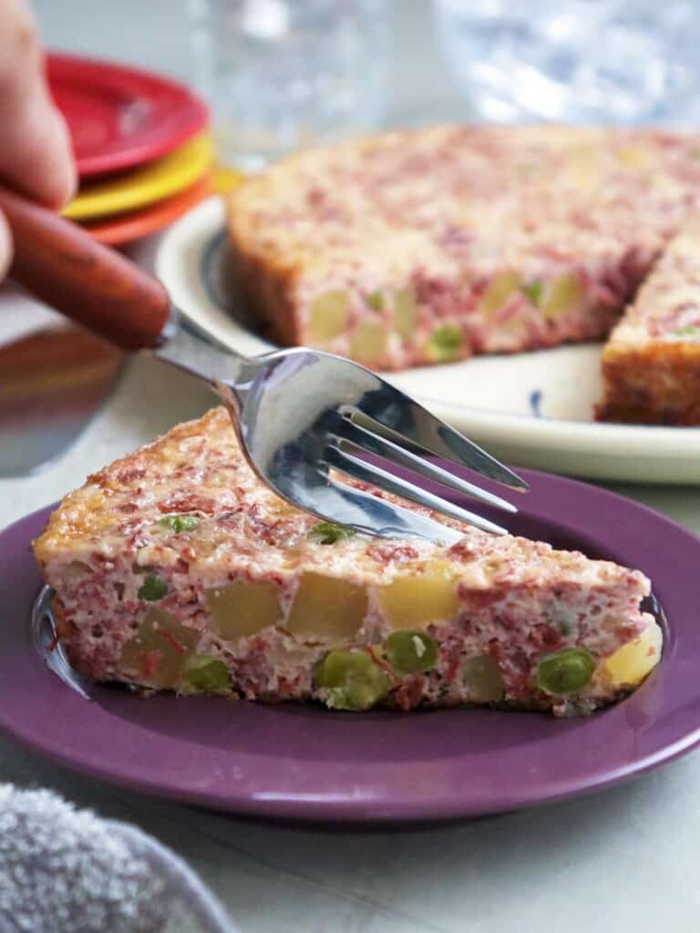 slice of frittata with corned beef, potatoes, and eggs on serving plate