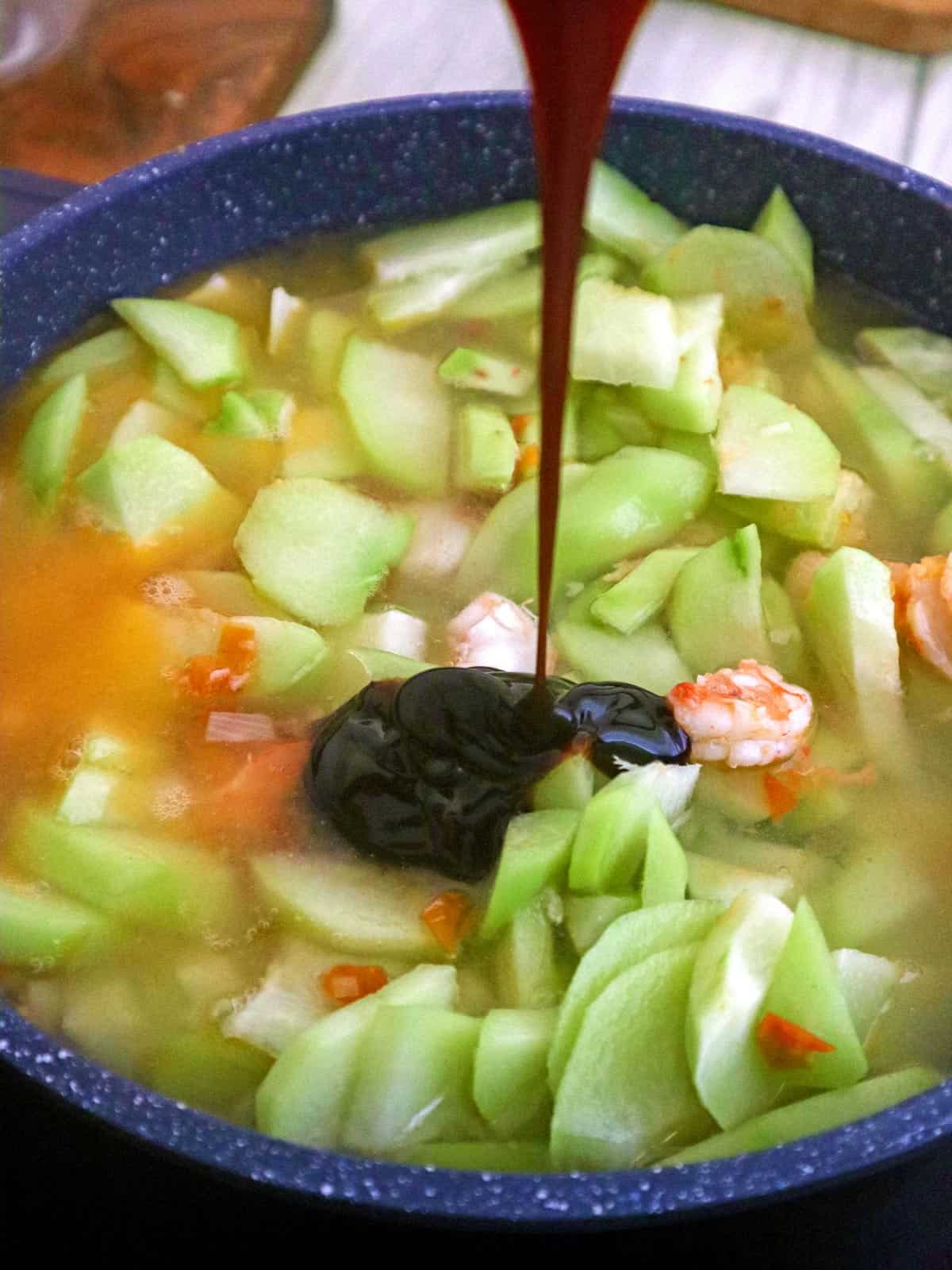 adding oyster sauce to sayote guisado in the pan