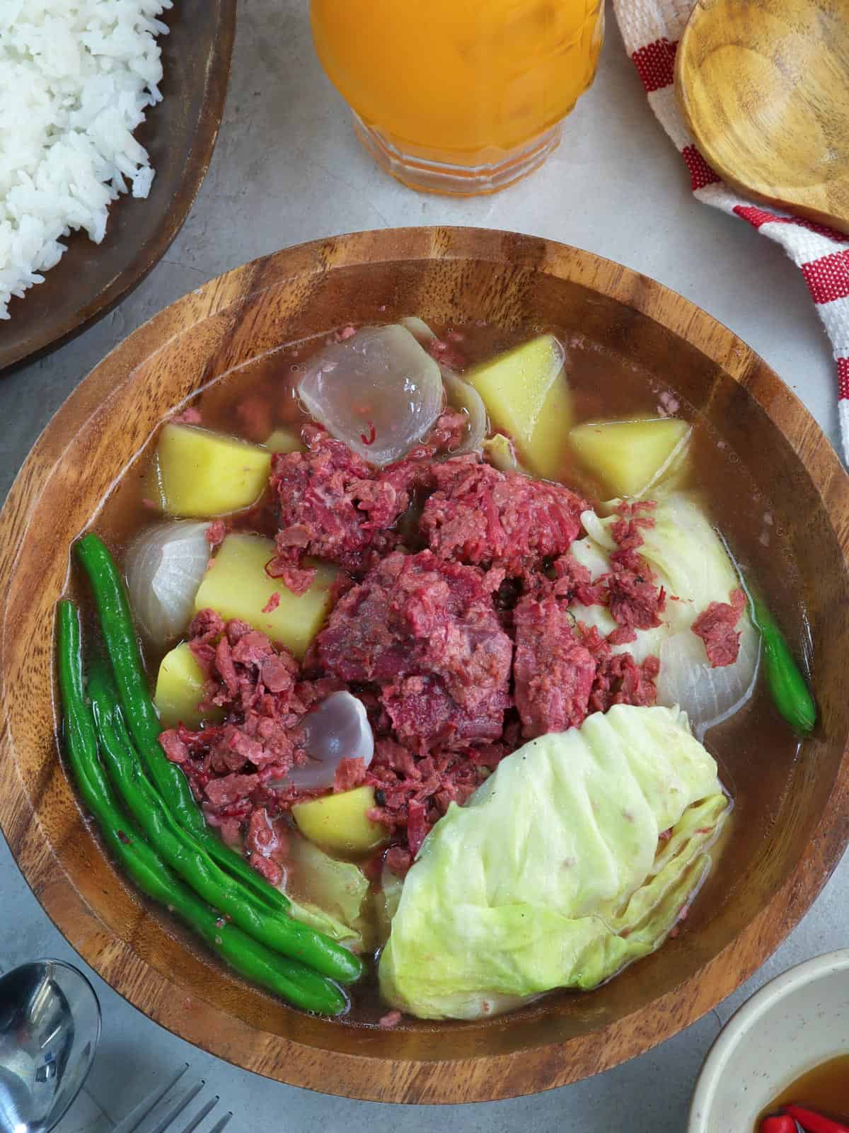 corned beef nilaga in a wooden bowl with a plate of rice on the side