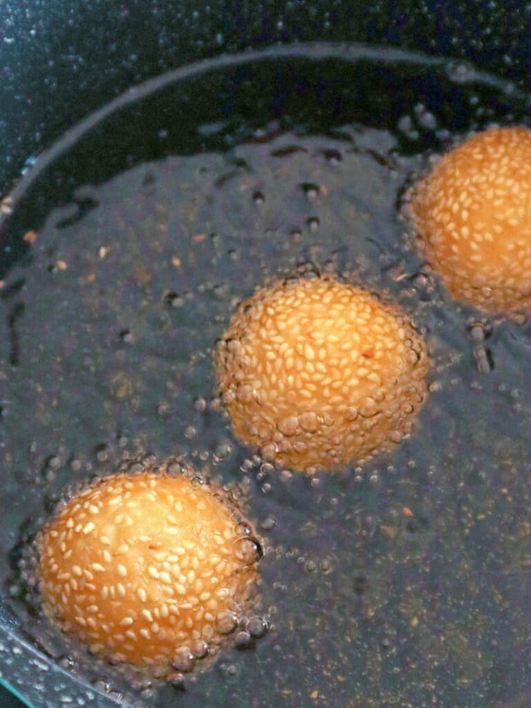 frying sesame seed balls in a pot of hot oil